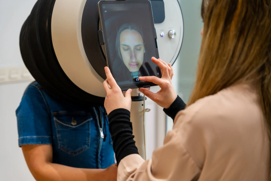 Behandler scanner en kundes ansigt med et hudanalyseapparat